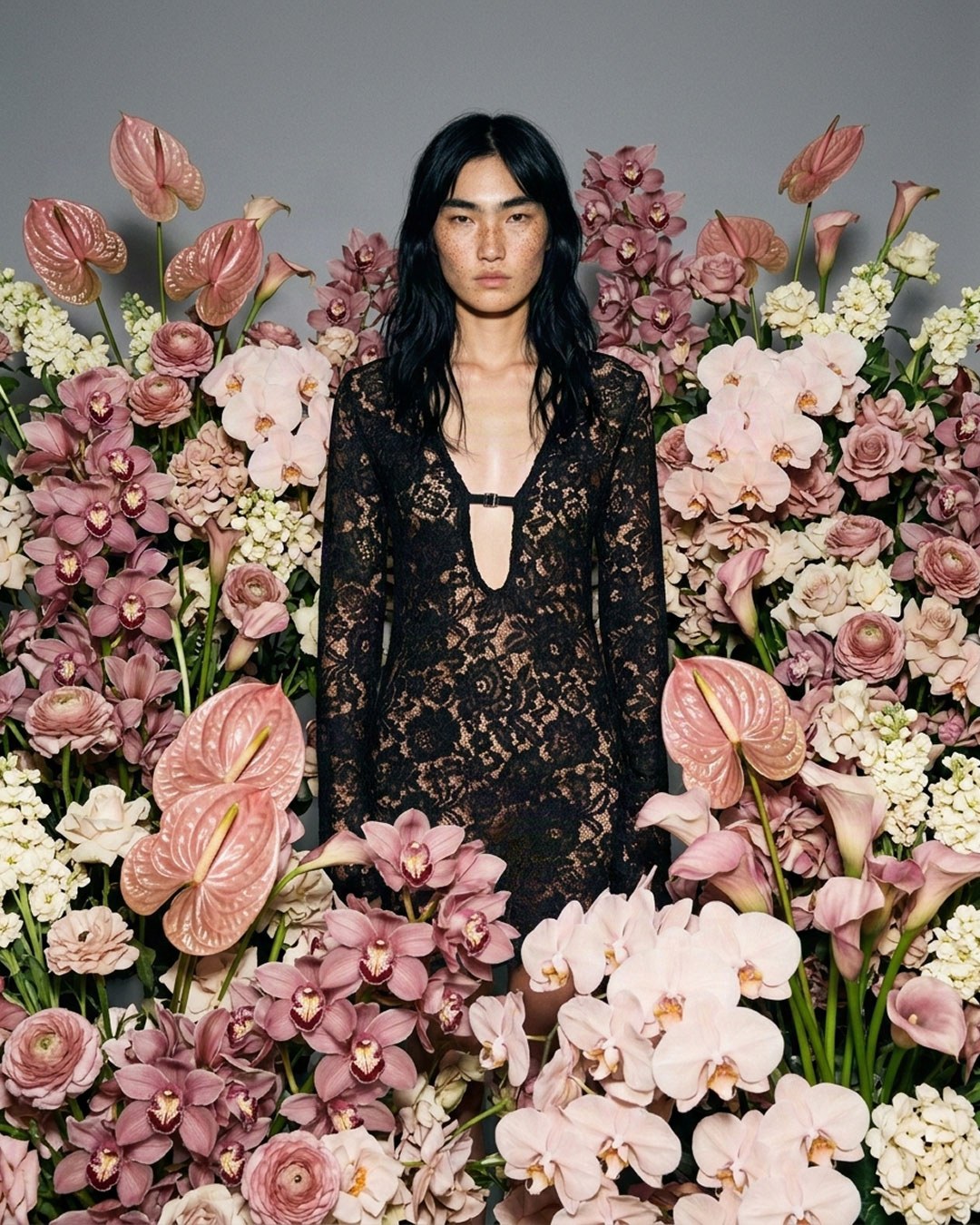 MISHIMONO spec editorial model in a black lace dress centered among pink anthuriums and orchids
